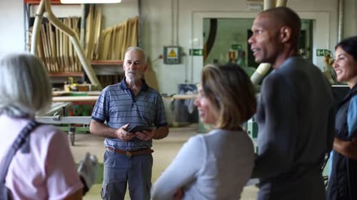 Senior Carpenter Leading a Woodworking Class in Workshop
