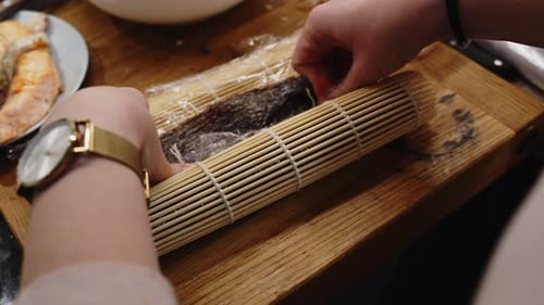 Hands Making Sushi Roll With Bamboo Mat