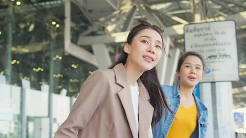 Duas mulheres asiáticas esperando um ônibus depois de sair do aeroporto.