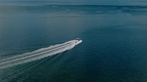 Aerial Wide View of a White Boat Sailing to the Blue Sea Moving at High Speed