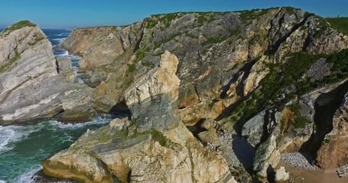 Aerial View Ursa Beach Atlantic Coastal Surf with Foamy Waves Crashing Over Big Rocky Cliffs