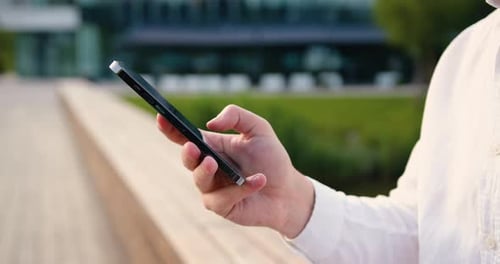Close up of males hands use mobile phone outdoors