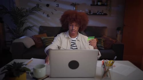 Concentrated Latin Man Shops at Online Store Home at Night Young Afro Male Sitting on Living Room