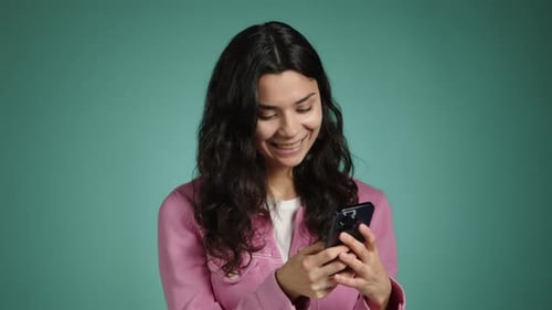 Smiling Woman Uses Smartphone Against Blue Background