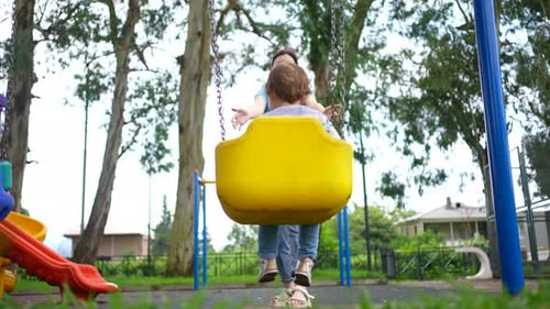 a Joyful Mother and Child on a Swing on the Playground the Happiness of Motherhood