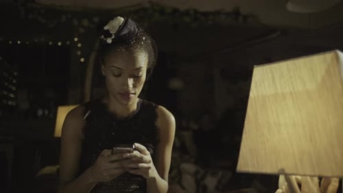Glamorous woman using phone indoors at night