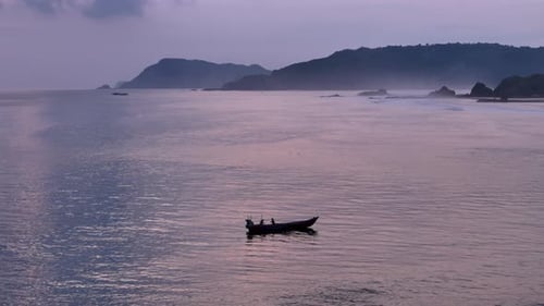 Boat glides on calm sea during twilight with misty mountains in the background