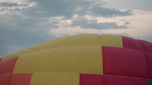 Gold Red Balloon Envelope Rising Over Grassy Field Under Pastel Sky