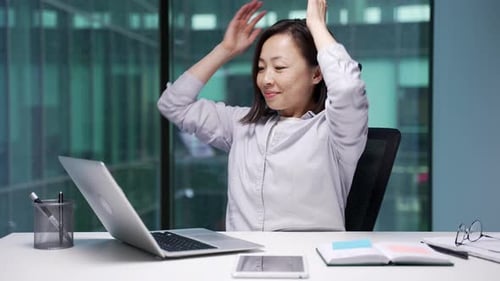 Happy asian businesswoman finished work on laptop sitting at workplace in business office. Smiling