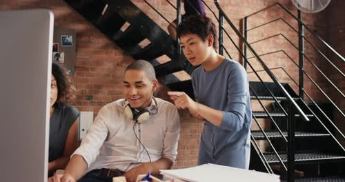 Happy, diverse network design team working together, using a computer at a startup