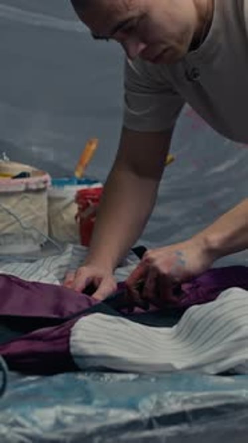 Vertikal eines jungen, konzentrierten Handwerkers, der die Jacke in der Werkstatt neu entwirft