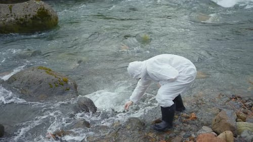a Biologist in a Protective White Jumpsuit Tests the Water Quality in the River Wide View