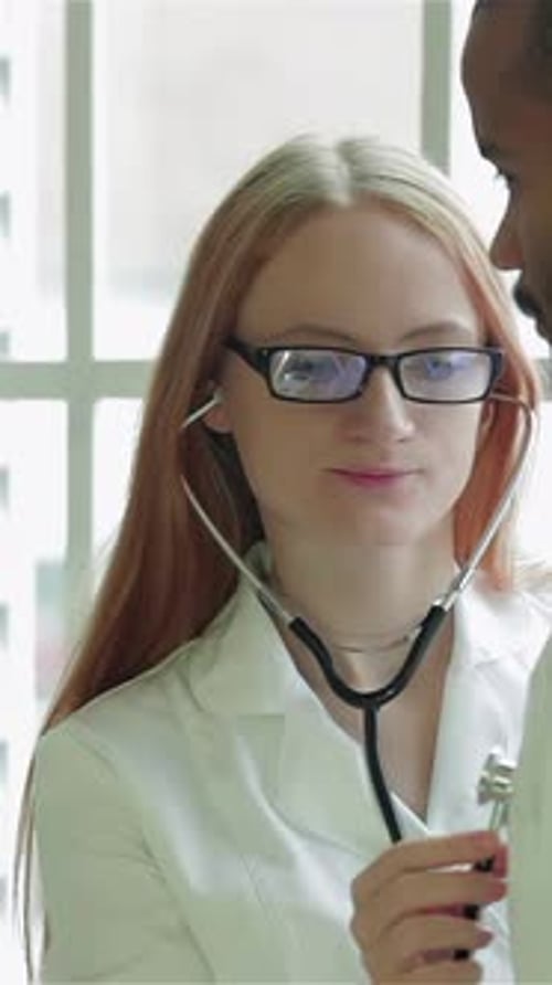 Doctor Attentively Listens to Patient's Chest with a Stethoscope