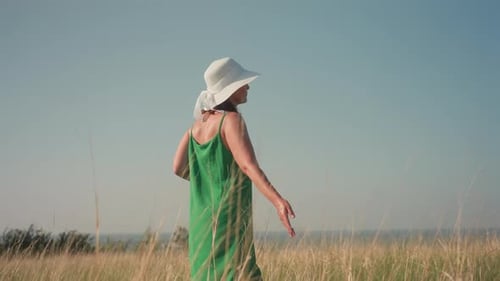 Confident Woman Walking Through Dry Grassy Field with Camera in Hand