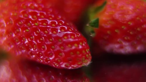 detailliertes Video eines Erdbeerhaufens, rote RAW-Erdbeere, grünes Blatt, winzige Samen, auf einem rotierenden