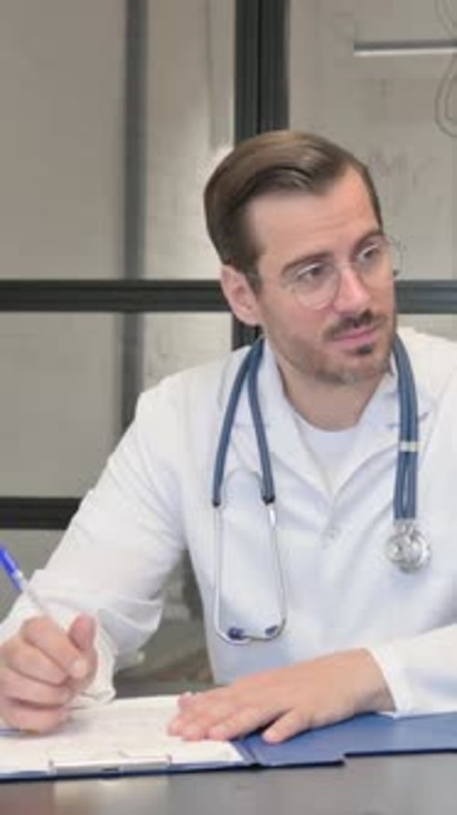 Doctor Writing on Chart While at Desk