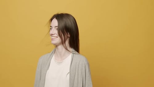 Smiling Woman Tilting Head on Yellow Background