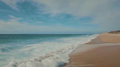 Powerful ocean tides moving towards the tropical sandy beach, creating white wash.