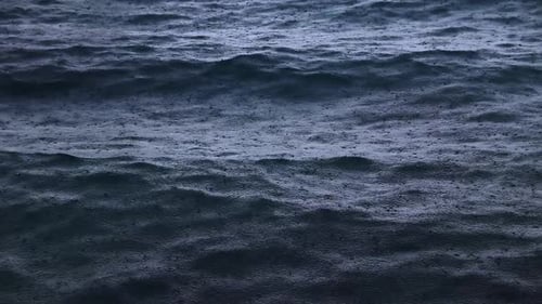 Nahaufnahme von Regentropfen, die auf die Meeresoberfläche fallen und ihr ein abstraktes, hypnotisches und mystisches Aussehen verleihen
