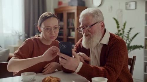 Young Woman and Senior Man Using Smartphone