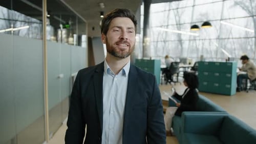 Smiling Man Walking Confidently in Modern Office Environment
