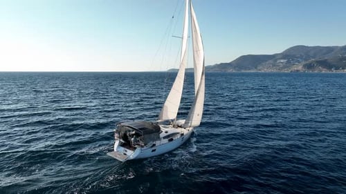 Sailboat Gliding Across Ocean on Sunny Day