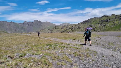 Deux routards font de la randonnée sur un sentier dans une vallée montagneuse en haute altitude