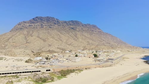 Aerial View of a Coastal Settlement and Desert Town Located at the Base of Rugged Mountains Along