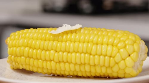 I place a piece of butter on the hot cooked corn, and it slowly melts.