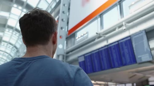 Guy looking at flight schedule board. Man in international airport looking at the flight information