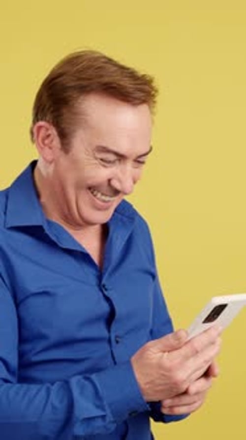 Man Smiles While Looking at Smartphone