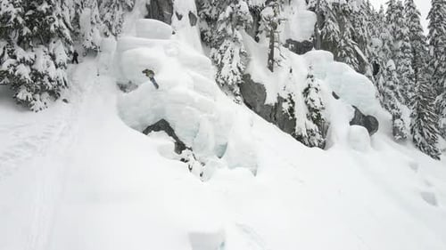 Snowboarder Descends Through Snowy Mountain Landscape