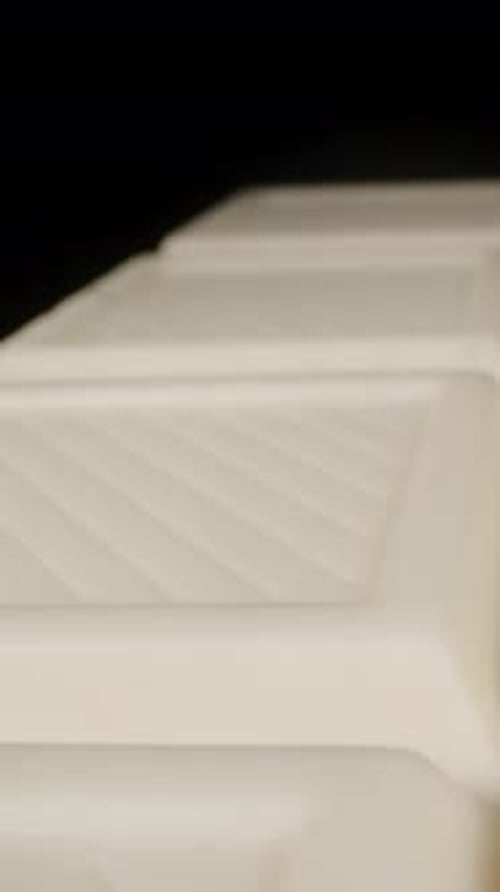 A white chocolate bar seems to levitate on a black background. Isolated. Vertical video.