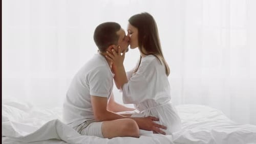 Romantic Couple Kissing in a Brightly Lit Bedroom