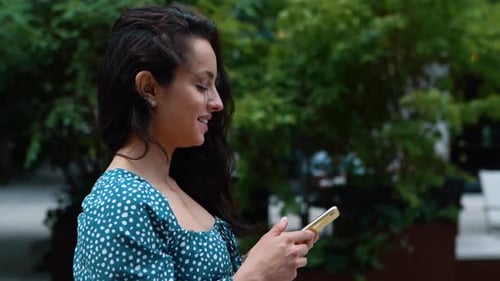 Close Up of Young Beautiful Woman Texting Message on Smartphone on Social Media While Walking in