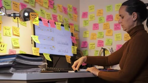 Woman Working Hard at Desk Covered in Notes