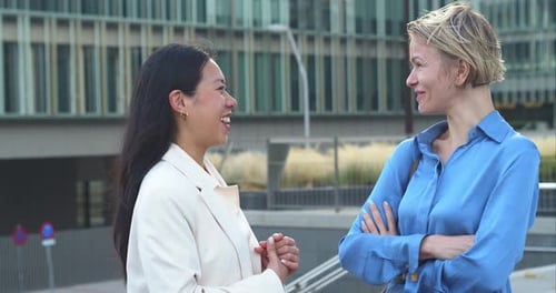 Two Business Women Talking to Each Other Happily in a Financial District Business Colleagues