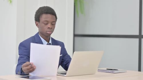 Young Adult Working On Laptop in Modern Workplace