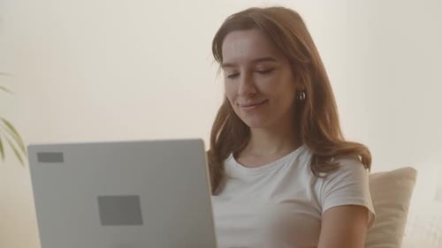 Brunette Girl Using a Computer A Young Woman is Writing a Study Project Using a Laptop Female