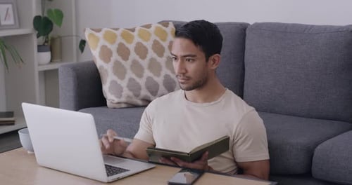 Male student researching on laptop and writing notes