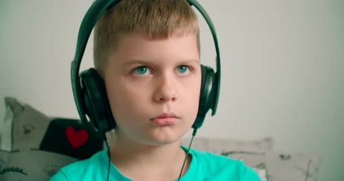 Boy Listens to Music on Black Headphones