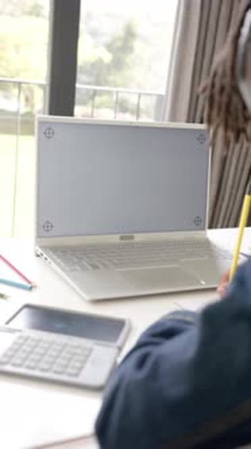 Vertical video of african american boy using laptop with copy space on screen at home, slow motion