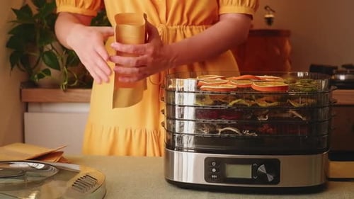 Woman Packing Dried Fruit From Dehydrator Into Bag