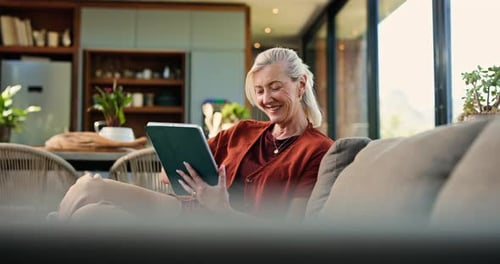 Smiling Senior Woman Using Tablet on Couch at Home