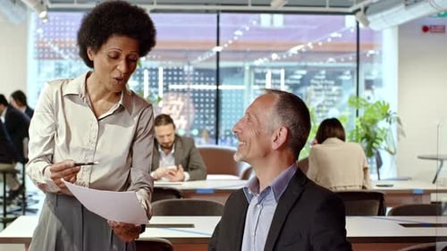 Woman Explains Document to Man in Office Setting