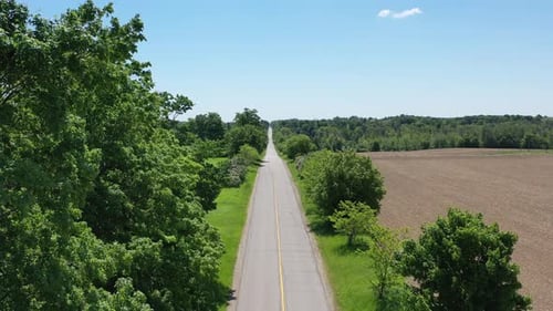 Aerial view of black sports car driving through a rural scene