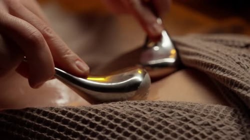 Nahaufnahme einer beruhigenden Spa-Behandlung mit Metallmassagegeräten und Öl zur Entspannung des therapeutischen Körpers