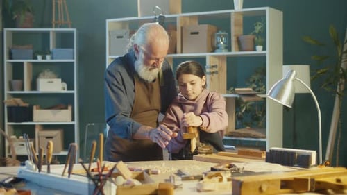 Teenage Girl with a Caring Grandfather Carpenter Learning to Works with Wood