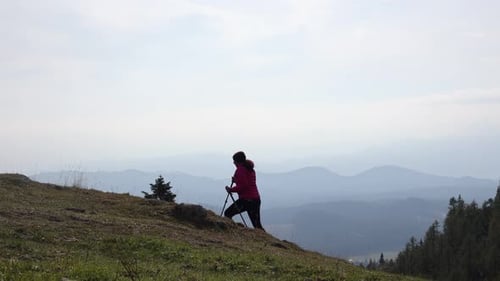 Woman Hikes on Mountain with Walking Sticks