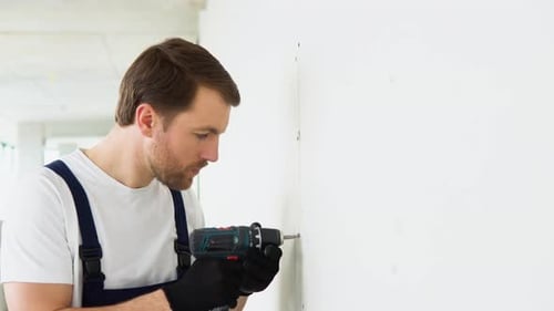 Man Using Electric Drill on Wall